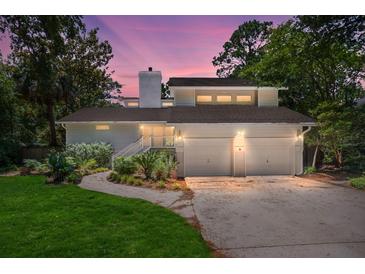Inviting home exterior with a two-car garage, well-maintained landscaping, and charming curb appeal during twilight at 3 Sand Dollar Dr, Isle of Palms, SC 29451