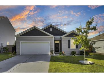 Charming single-story home with a two-car garage and a well-manicured lawn at sunset at 545 Wayton Cir, Moncks Corner, SC 29461