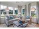 Sunroom features a comfortable gray sofa and wicker chair, large windows, and natural light at 173 Fiddleback Dr, Summerville, SC 29486