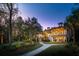 Landscaped backyard with lit pathways leading to a large house at dusk at 633 Barbados Dr, Charleston, SC 29492