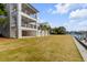 Large backyard with lush green grass and a great view of the house's multiple stories and balconies at 34 Waterway Island Dr, Isle of Palms, SC 29451