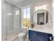 Modern bathroom featuring a glass-enclosed shower, blue vanity, and a round mirror with stylish lighting at 34 Waterway Island Dr, Isle of Palms, SC 29451