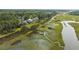 Aerial view of waterfront homes nestled in lush greenery, featuring a marsh and dock along the calm water at 1560 John Fenwick Ln, Johns Island, SC 29455