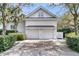 Two car garage with brick paver driveway surrounded by lush landscaping with mature trees at 143 Island Park Dr, Charleston, SC 29492