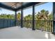 Large outdoor porch with views of palm trees, dark blue wood paneled columns, and light stone floors at 615 Pompano St, Edisto Island, SC 29438