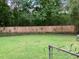 Large backyard featuring a wooden fence, green grass, and mature trees creating a private outdoor space at 7700 Midwood Dr, North Charleston, SC 29420