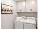 Functional laundry room with washer, dryer, storage cabinets, and laundry-themed art at 111 Ashley Cove Way, Summerville, SC 29483