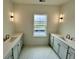 Bright bathroom with dual vanities, tiled floor, modern lighting and a window with an outdoor view at 180 Sandy Bend Ln, Summerville, SC 29486