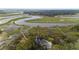 Aerial view of a house situated among trees, with a river and docks nearby at 8272 Palmetto Rd, Edisto Island, SC 29438