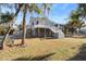 Charming white home elevated on pilings with a screened porch and wrap around porch, set amongst mature trees at 8272 Palmetto Rd, Edisto Island, SC 29438