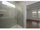 A frameless glass shower door leads to a light-filled bedroom featuring rich hardwood flooring at 741 Blue Iris Way, Summerville, SC 29486