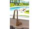 Modern kitchen sink with gold faucet and view of backyard pool at 769 Bulls Bay Blvd, Awendaw, SC 29429