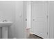 A modern bathroom features white walls, vinyl flooring, a pedestal sink and a door to another room at 373 Willows Crescent Dr, Moncks Corner, SC 29461