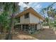Two story exterior of home featuring a screened porch, beige paint, and lush tropical landscaping at 818 Club Cottage Court, Edisto Beach, SC 29438