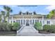 Elegant two-story white brick home featuring dormer windows and a welcoming front porch with columns and manicured landscaping at 1000 Rivershore Rd, Charleston, SC 29492