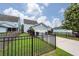View of the garage and yard with green grass and a black metal fence at 208 Sweetspire Ln, Summerville, SC 29483