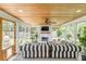 Relaxing screened porch with fireplace, comfy striped sofa, and ceiling fan at 1466 Glencoe St, Mount Pleasant, SC 29464