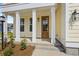 Inviting front entrance with wood door, yellow siding, white columns, and craftsman-style exterior lighting at 506 Fiskdale Cir, Summerville, SC 29486