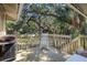 Outdoor deck featuring a relaxing white rocking chair and grill, surrounded by lush trees at 1101 Summerwind Ln, Seabrook Island, SC 29455