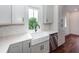 This kitchen features white cabinets, stainless dishwasher, chevron backsplash, hardwood floors and a large farmhouse sink at 24 Iron Frg Aly, Charleston, SC 29403