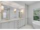 Elegant bathroom featuring double vanity with marble countertops, gold fixtures, and a soaking tub with natural light at 517 Royall Ave, Mount Pleasant, SC 29464