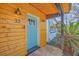 Close-up of the turquoise-painted front door set in wood siding, accented by stylish light fixtures and hanging plants at 32 Briarcliff Dr, Charleston, SC 29407