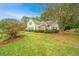 Exterior view showing the home's tan siding, brick accent, and mature trees in a well-maintained yard at 177 Thousand Oaks Cir, Goose Creek, SC 29445