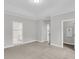Open bedroom with a neutral carpet, tray ceilings, a window, and easy access to an adjoining bathroom at 357 Wappoo Trace Ln, Summerville, SC 29486