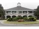 Grand clubhouse with white brick facade, covered porches, and manicured landscaping conveys a sense of luxury at 3105 Sturbridge Rd, Mount Pleasant, SC 29466