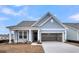 Beautiful home featuring an attached two-car garage and a welcoming front porch, complemented by a well-maintained lawn at 317 Abercom Place Dr, Moncks Corner, SC 29461