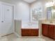 Bright bathroom featuring a soaking tub, white vanity, and neutral tile floors at 1129 Plantation Overlook Dr, Moncks Corner, SC 29461
