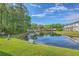 A picturesque pond with lush green banks and a reflection of the community buildings under a sunny sky at 605 Pond Pine Trl, Summerville, SC 29483