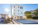 Three-story beach home with white exterior and open parking at 1579 E Ashley Ave, Folly Beach, SC 29439