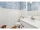 Stylish powder room with blue leaf wallpaper, white vanity, and wood-look flooring at 2972 Anchor Watch Dr, Wadmalaw Island, SC 29487