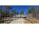 Charming single-story home with gray siding, white trim, and a gravel driveway surrounded by tall, mature trees at 392 Dike Rd, Bonneau, SC 29431