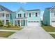 Two-story light teal house with white garage door and landscaping at 1016 Swamp Harrier Ave, Ravenel, SC 29470