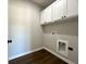 Functional laundry room with white cabinets, base molding, and wooden-look flooring at 1081 Irving Manigault Rd, McClellanville, SC 29458