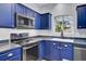 Stylish kitchen featuring blue cabinetry, stainless steel appliances, and a window at 1401 Churchill Rd, Moncks Corner, SC 29461