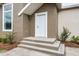 White front door with sidelights, leading to a raised entryway with steps and landscaping at 5344 Sea Watch Lane, North Charleston, SC 29406