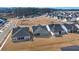 An aerial view showcases a new construction community with modern homes, lush lawns, and a tranquil, tree-lined backdrop at 1104 Cooper Point St, Summerville, SC 29485