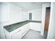 This laundry room features white cabinets, a green countertop, and ample natural light through two windows at 114 Groves St, Walterboro, SC 29488