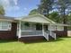 Charming brick home with a welcoming white porch, complemented by lush green lawn and decorative hanging plants at 127 Roberts Rd, Summerville, SC 29483