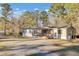 Tan mobile home with covered porch, American flag, and gravel driveway at 250 W Medina St, Summerville, SC 29483
