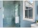 Modern bathroom with a glass-enclosed shower, blue tile, and a bright window at 6045 Honey Hole Haven, Johns Island, SC 29455