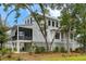 Stylish white house featuring a covered porch and an open living space underneath at 6045 Honey Hole Haven, Johns Island, SC 29455