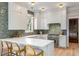 Bright kitchen features white cabinetry, a stylish backsplash, stainless steel appliances, and a marble countertop island with barstool seating at 6045 Honey Hole Haven, Johns Island, SC 29455