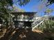 Rear view of house with screened porch, wooden stairs, and wooded area at 61 Twin Oaks Ln, Isle of Palms, SC 29451
