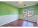 Empty bedroom with wood flooring, green walls, and white wainscoting at 8419 Creekstone Ct, North Charleston, SC 29406