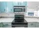 Kitchen features a stainless steel microwave and oven, light teal cabinets, and a white quartz countertop at 8419 Creekstone Ct, North Charleston, SC 29406