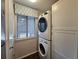 Bright laundry room with stacked washer and dryer, window with blinds, and white cabinets at 1530 Fort Johnson Rd # 2 K, Charleston, SC 29412